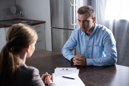 A man and a woman are sitting at a table talking to each other.