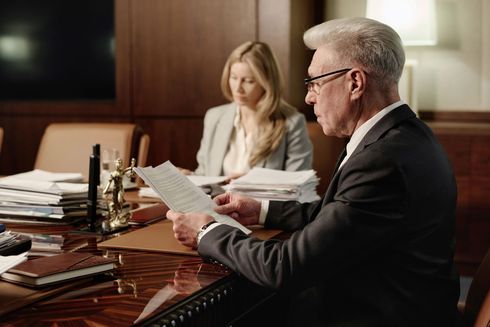 A man and a woman are sitting at a table looking at papers.
