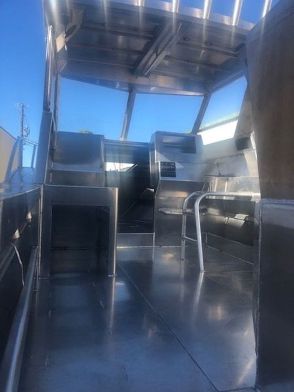The inside of a stainless steel boat with a blue sky in the background.