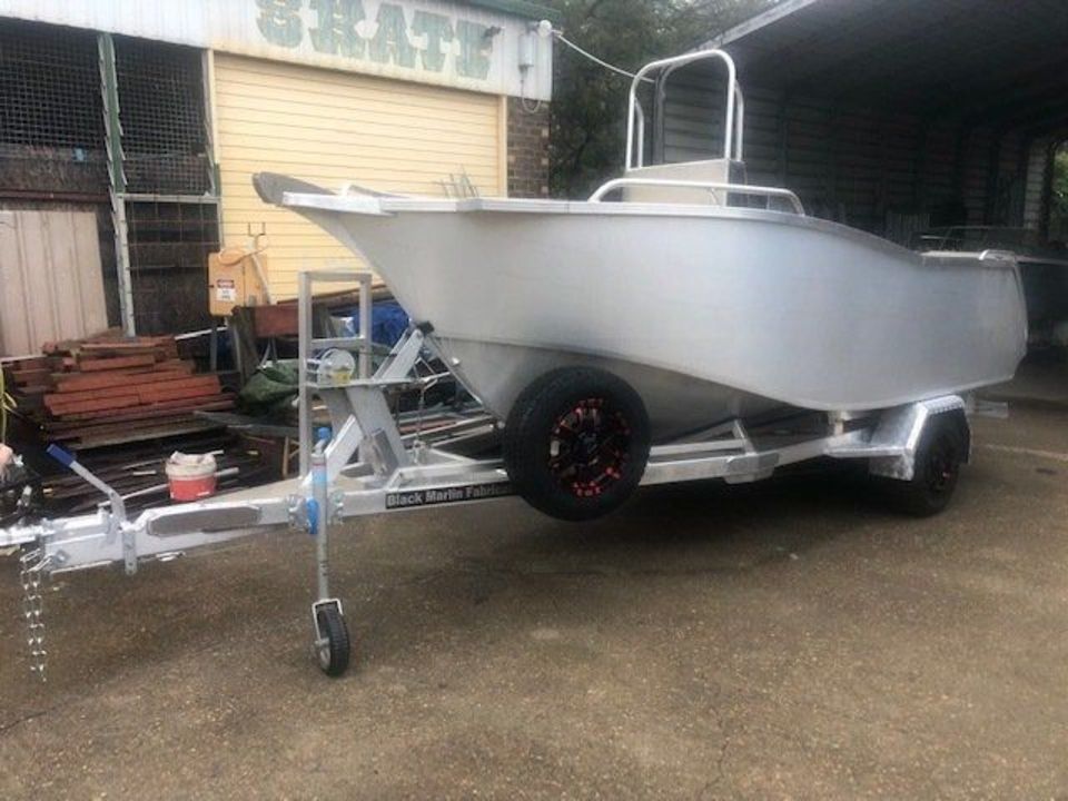A boat is sitting on a trailer in a parking lot.