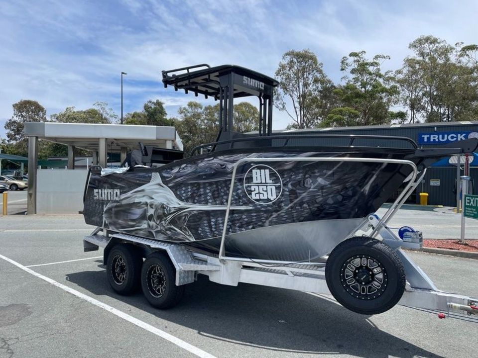 A boat is parked on a trailer in a parking lot.