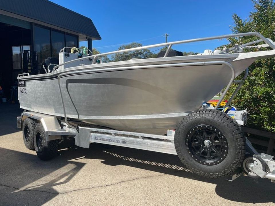 A silver boat is parked on a trailer in front of a building.
