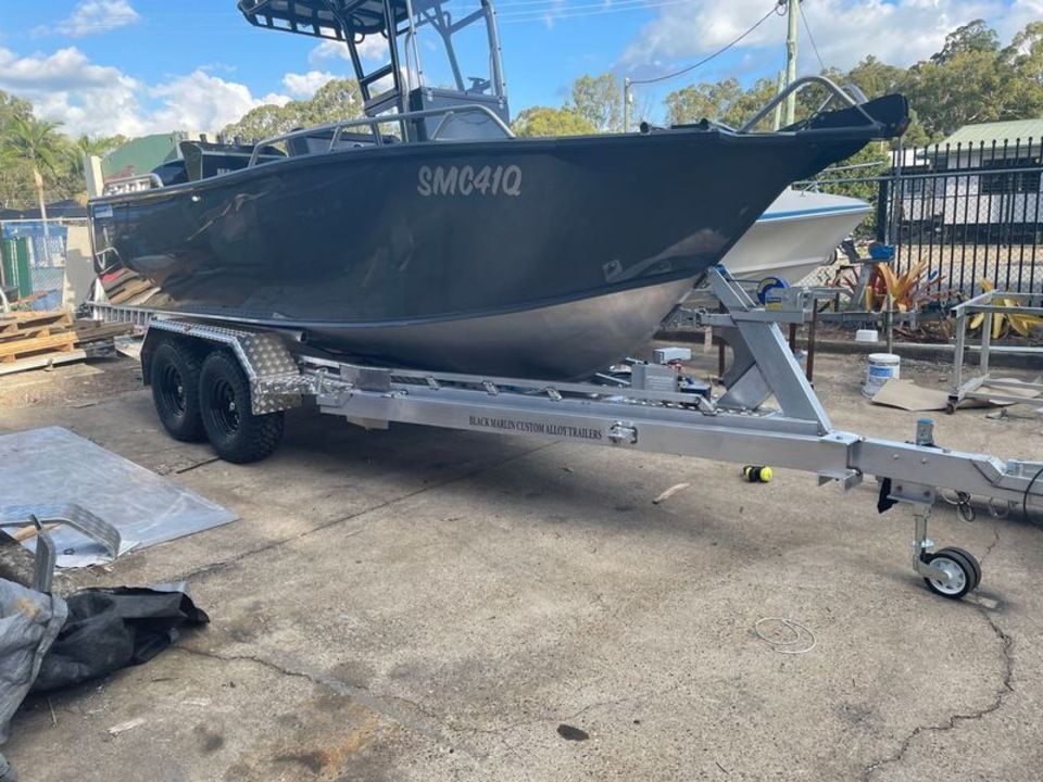 A boat is on a trailer in a parking lot.