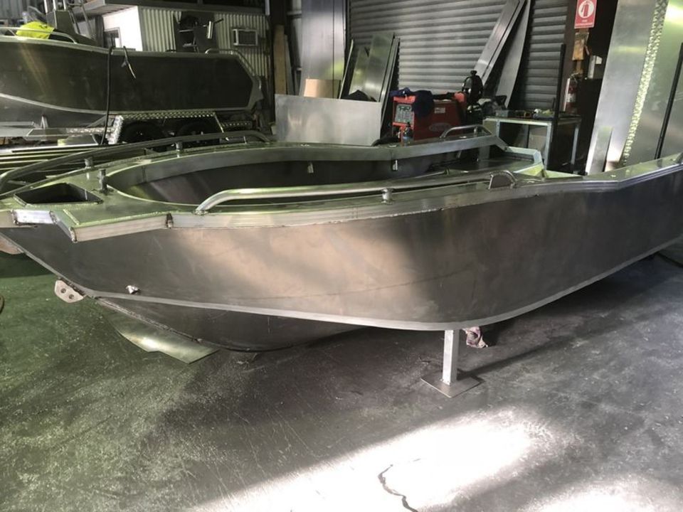 A stainless steel boat is being built in a factory.