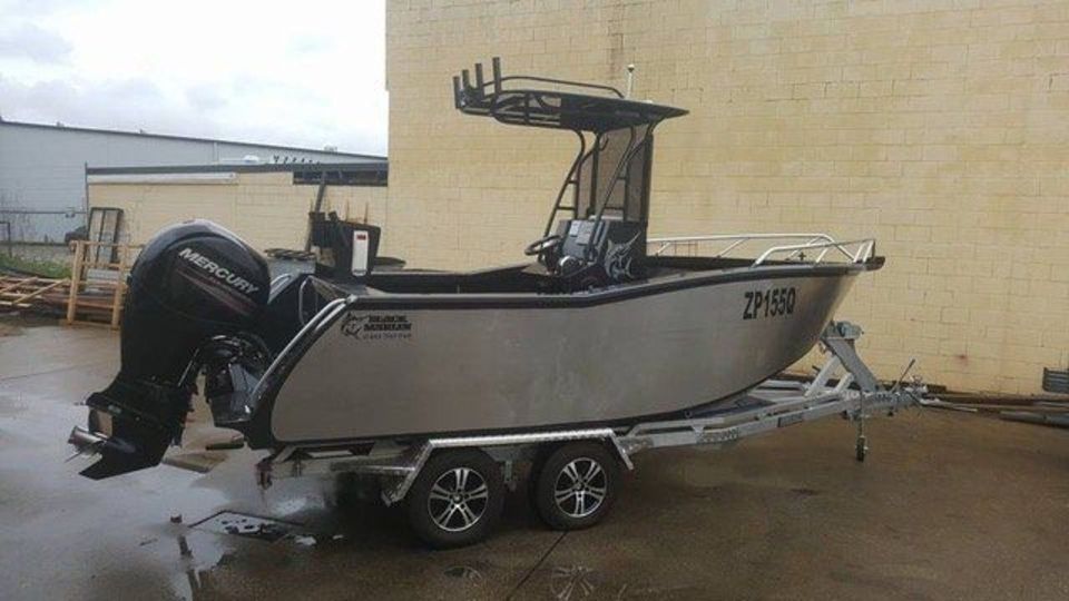 A boat on a trailer is parked in front of a building.