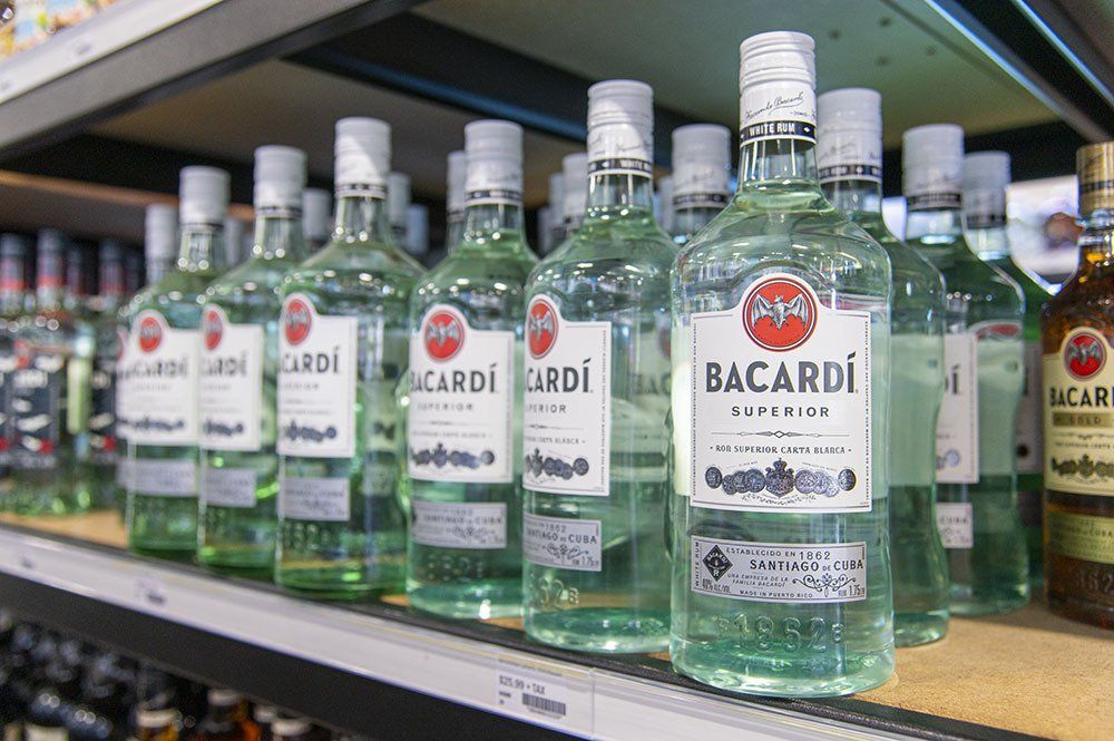 Bottles of Bacardi rum on a store shelf, with white labels and clear liquid.