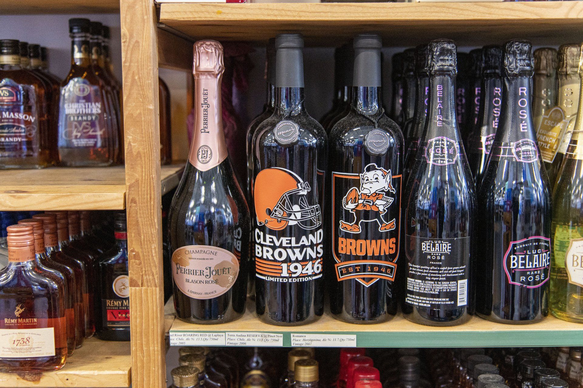 Bottles of wine, including Cleveland Browns themed bottles, on a shelf.