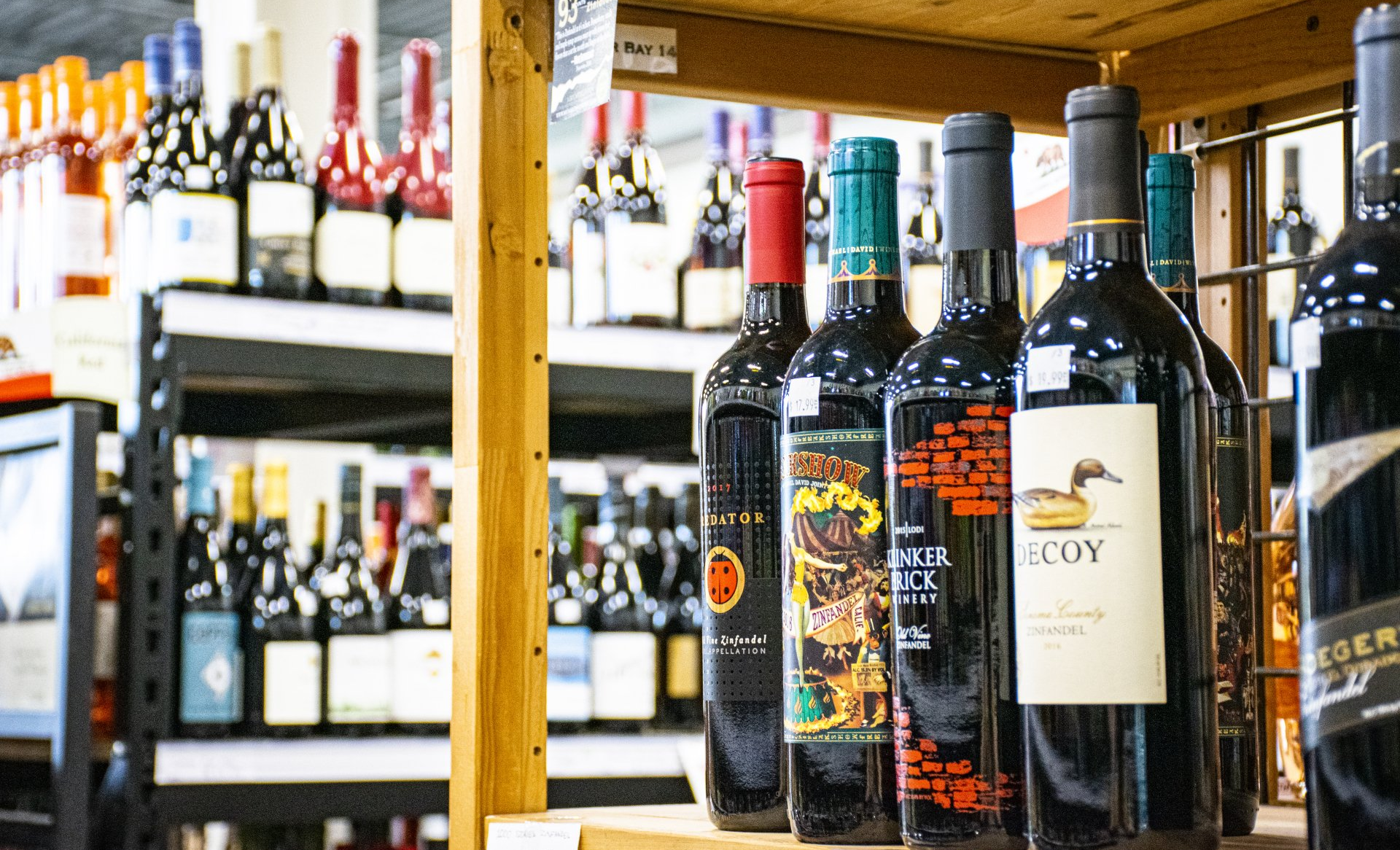 Wine bottles on a store shelf; various labels and colors.