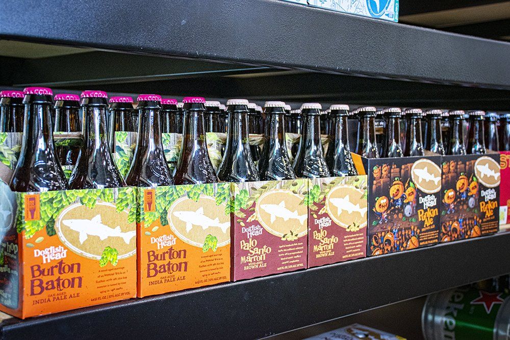 Bottles of beer in six-packs on a shelf. Labels include a white shark graphic and the words 