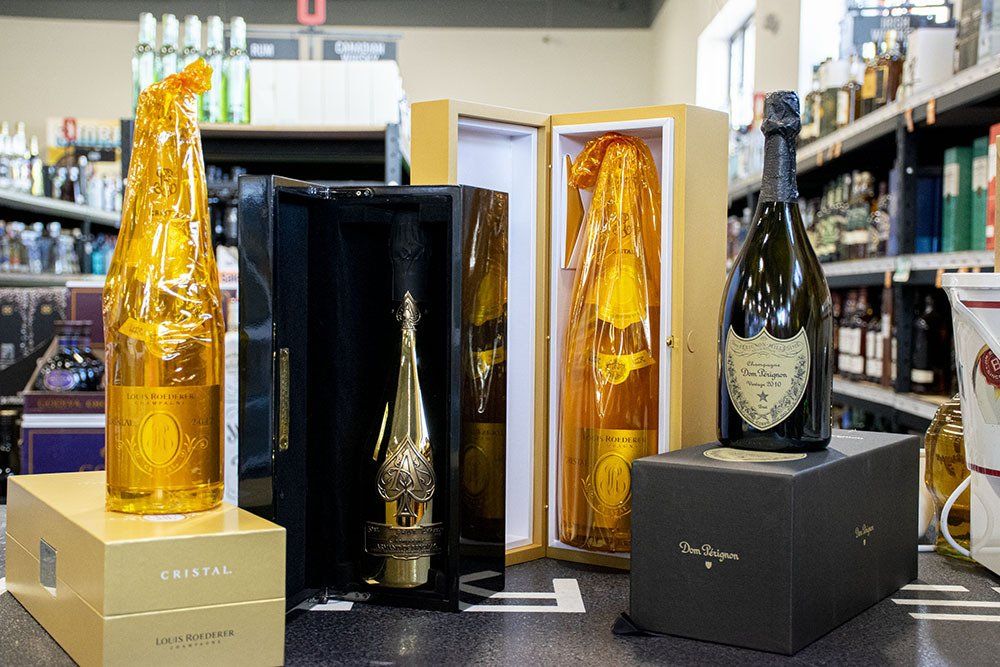 Champagne bottles displayed in gift boxes at a liquor store. Several are wrapped in gold foil.