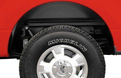 Black wheel well liner installed in a red truck bed, with a Michelin tire visible.