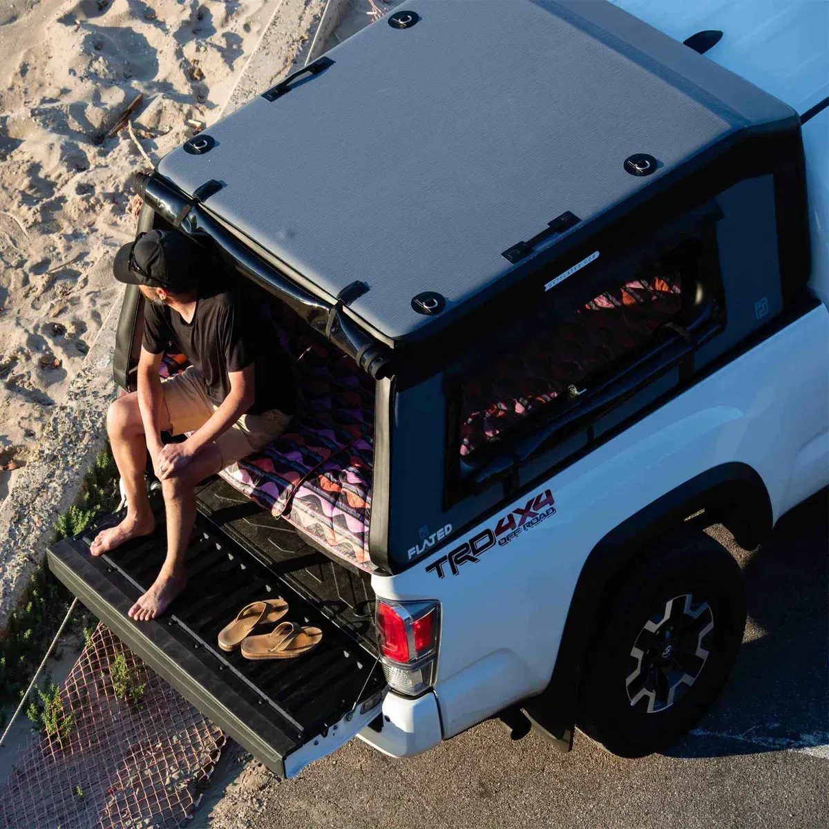 Person sitting in a flated air-topper, bed open, feet on tailgate.
