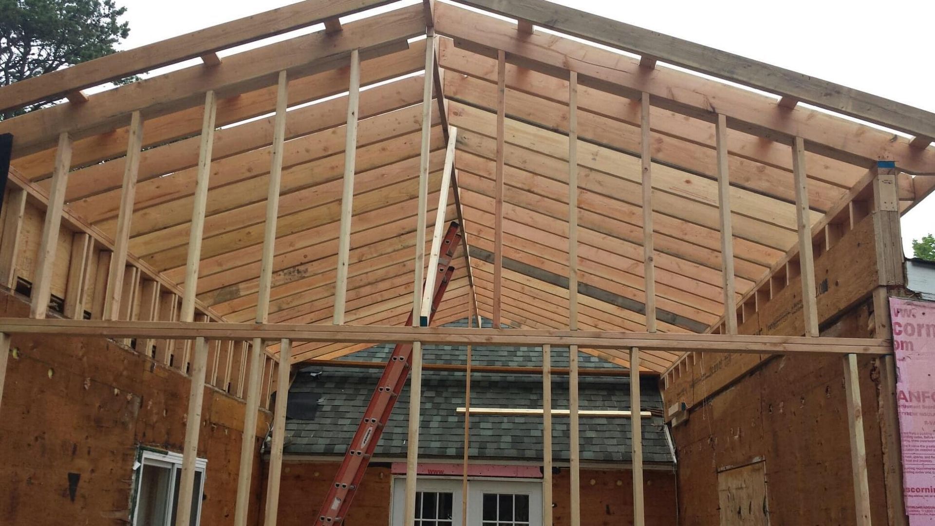 Wooden framing of a new roof structure under construction, seen from inside the unfinished building.