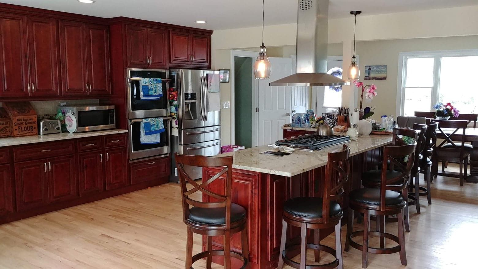 A kitchen with dark cherry wood cabinets, granite countertops, a center island with bar seating, and stainless appliances.