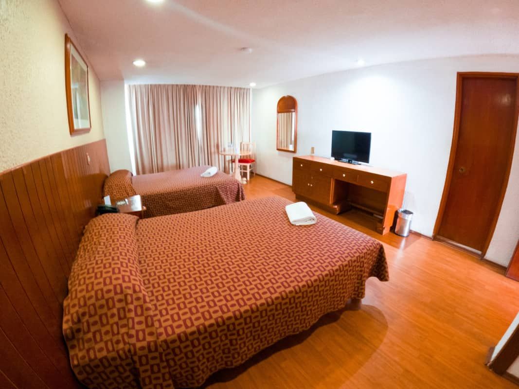 Una habitación de hotel con dos camas y un televisor de pantalla plana.