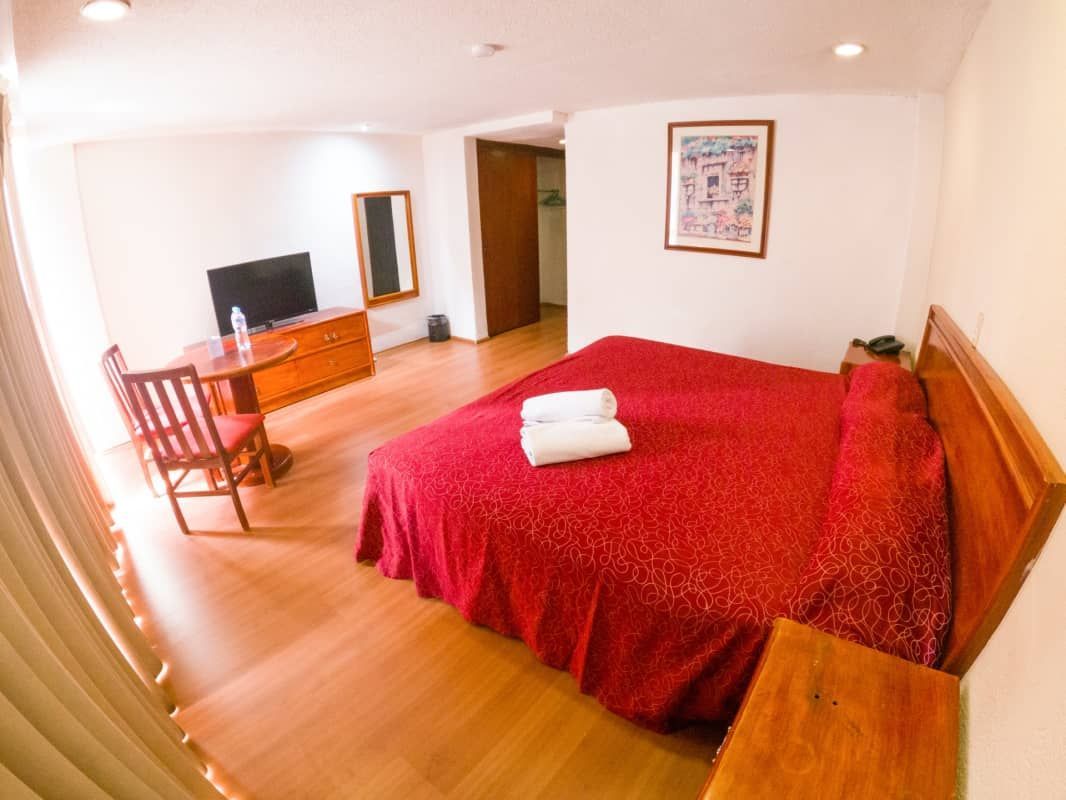 Una habitación de hotel con cama, silla, escritorio y televisión.