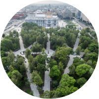 Una vista aérea de un parque con árboles y un edificio al fondo.