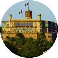 Un edificio grande con una bandera encima en un círculo rodeado de árboles.