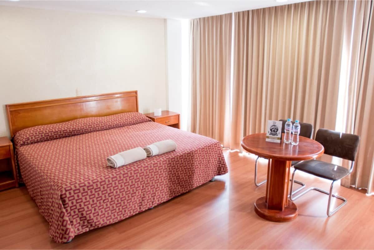 Una habitación de hotel con una cama tamaño king, mesa y sillas.