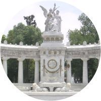 Hay una estatua en el medio de un parque rodeado de árboles.