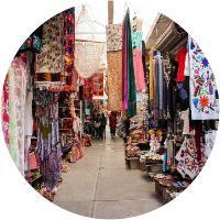 Un callejón estrecho lleno de ropa y paraguas.