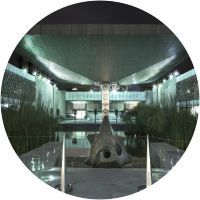 Un gran edificio con una fuente delante por la noche.