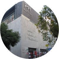 Un gran edificio con muchas ventanas está rodeado de árboles en un círculo.