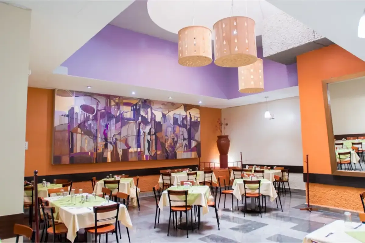 Un restaurante con mesas y sillas y un cuadro en la pared.