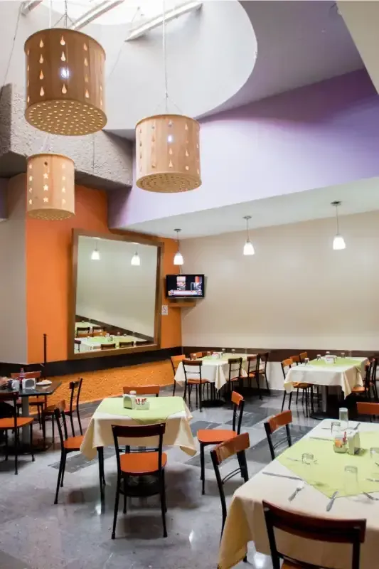 Un restaurante con mesas y sillas y un televisor en la pared.