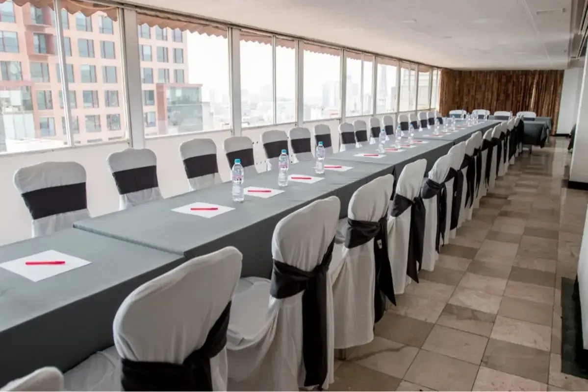 Una mesa larga y sillas en una sala de conferencias con muchas ventanas.