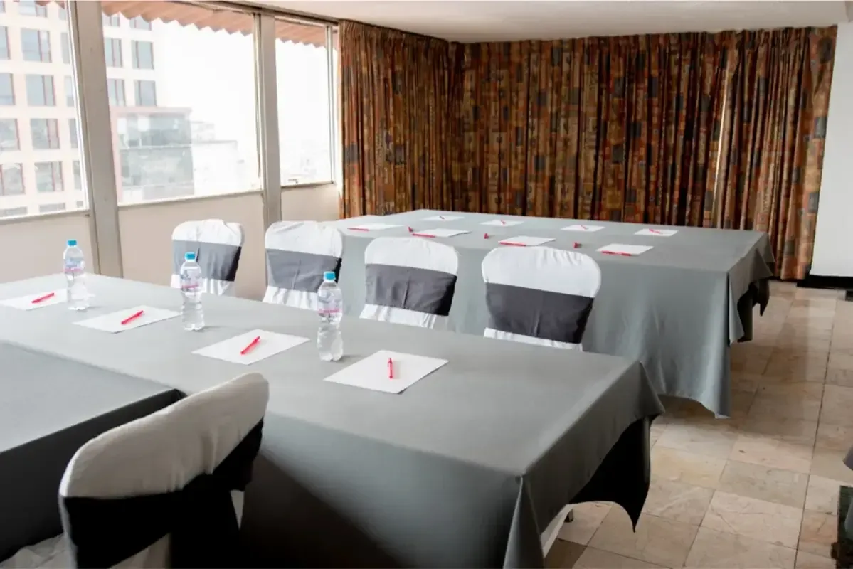 Una sala de conferencias con mesas y sillas preparadas para una reunión.