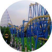 Una montaña rusa en un parque de atracciones con un cartel de Batman en primer plano.
