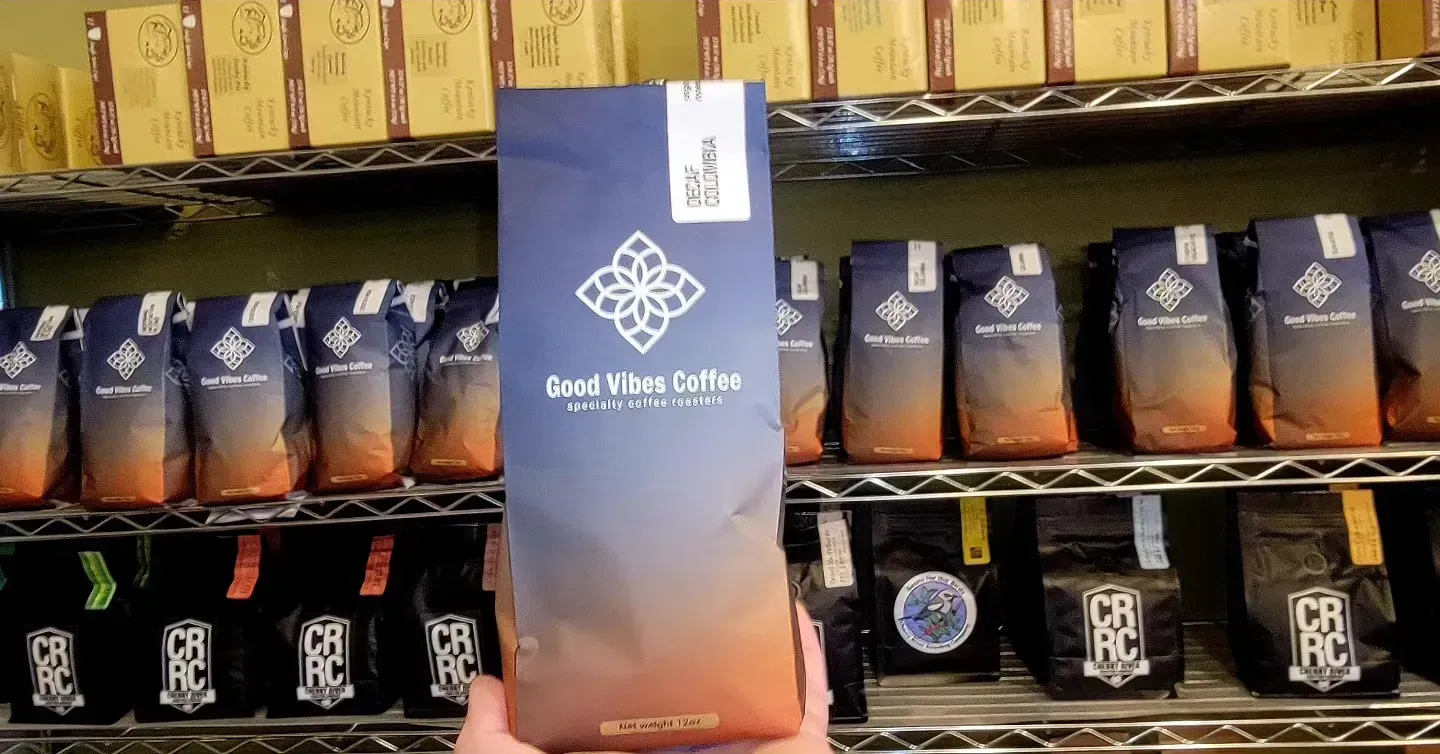 Coffee shop shelf with rows of dark coffee bags and a central Great North Coffee display sign.