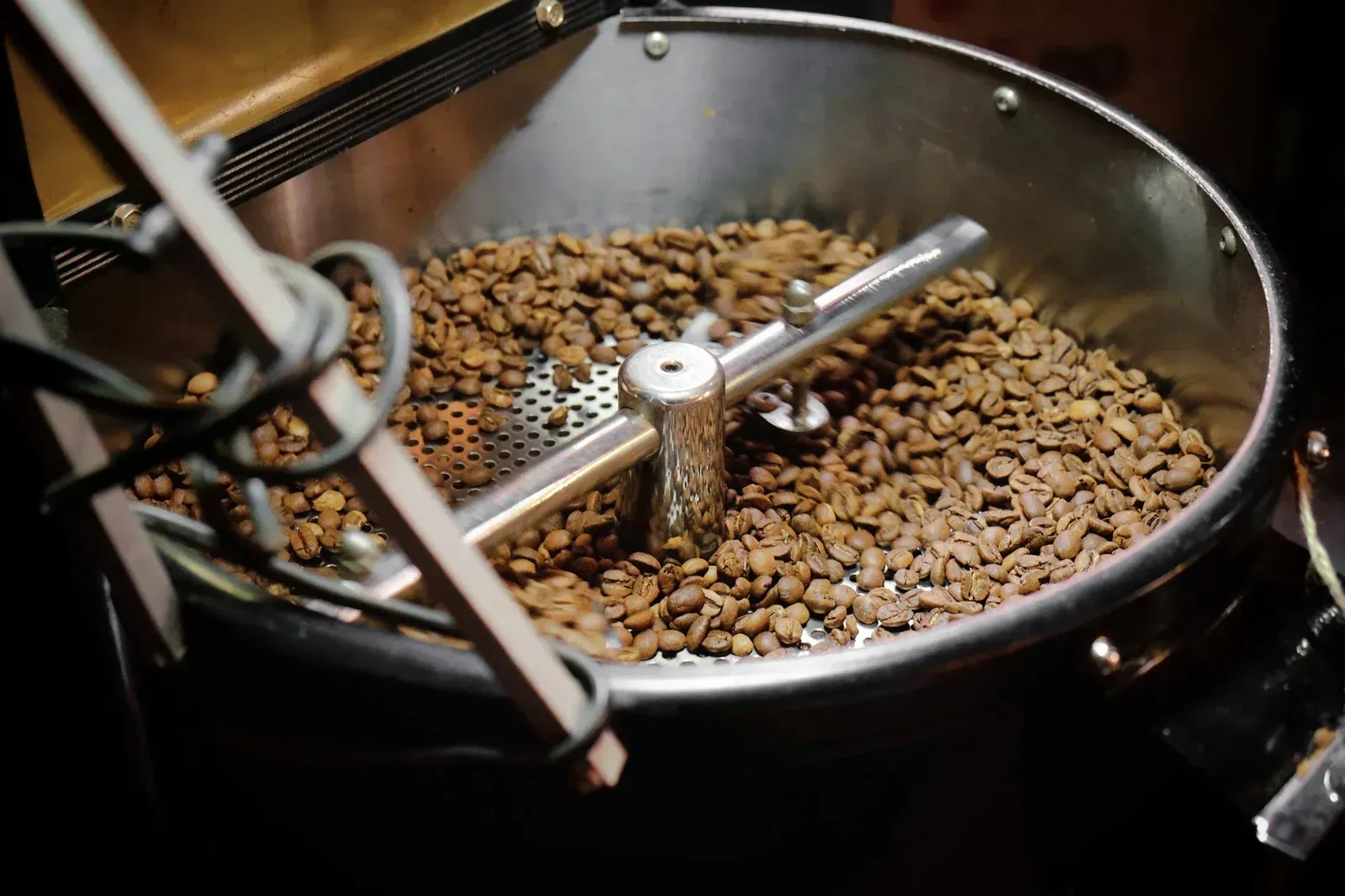 Coffee beans roasting in a metal drum roaster with rotating paddles