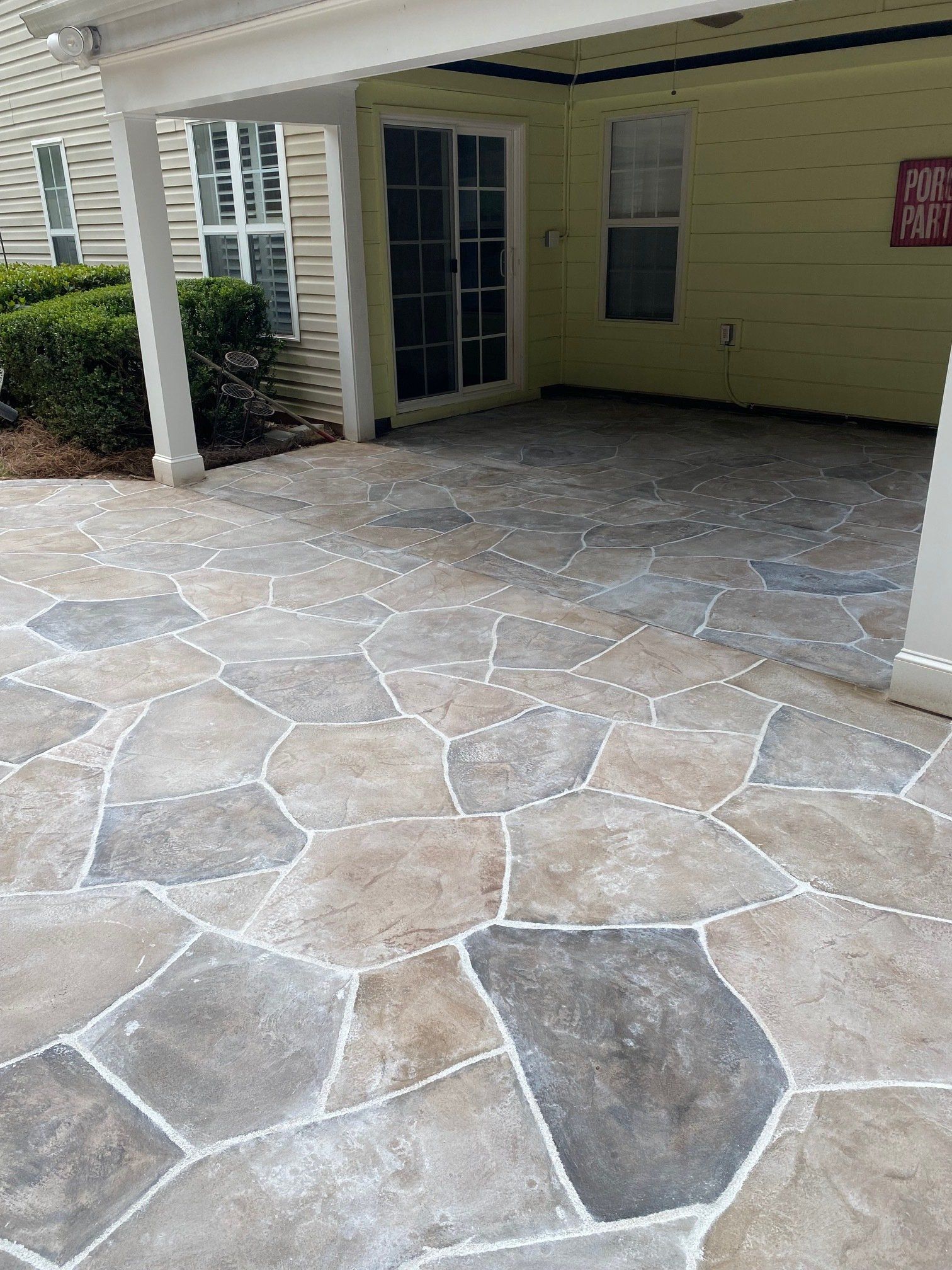 Covered stone-paver walkway leading to a porch with white columns and a blue door.