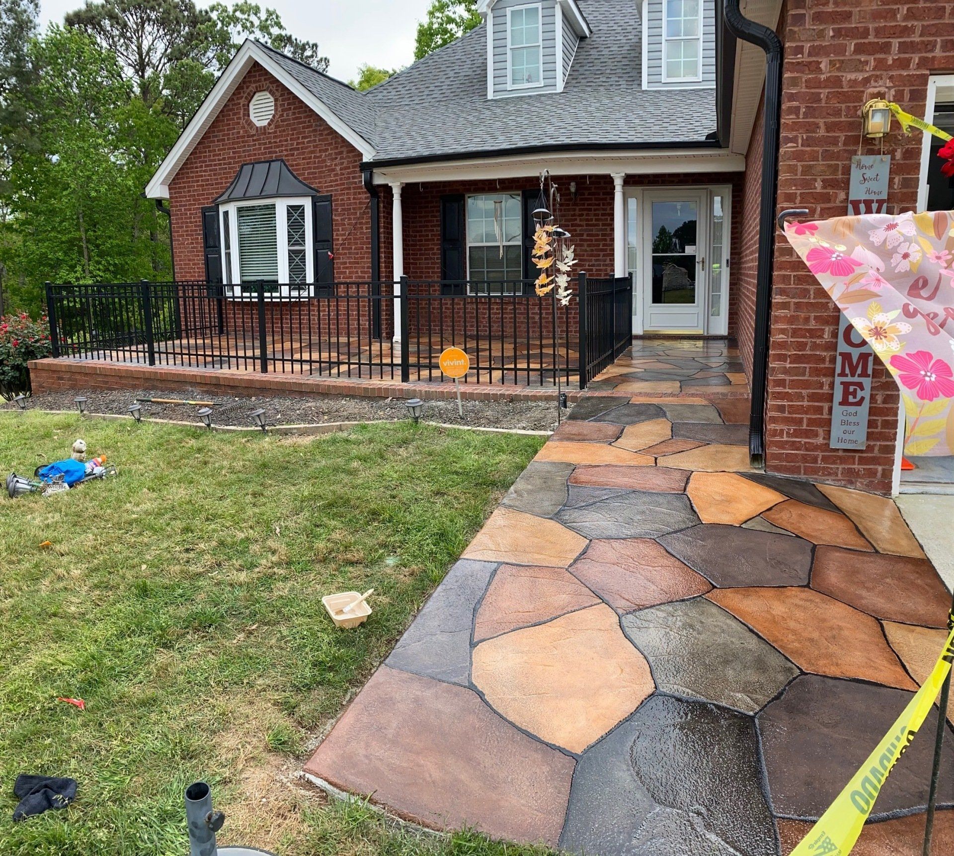 Brick house exterior with new stone walkway, front porch, and black metal railing