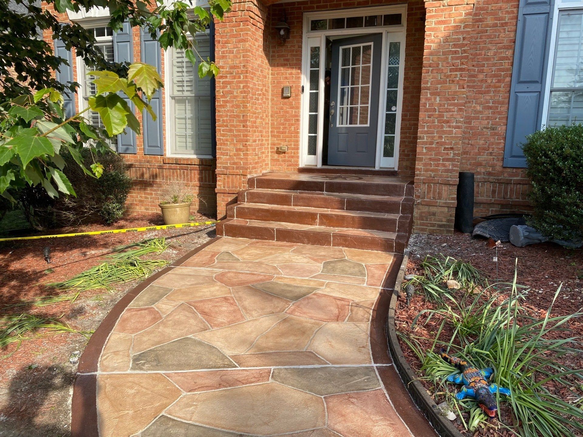 Brick walkway and steps leading to a front door of a brick house, bordered by landscaping