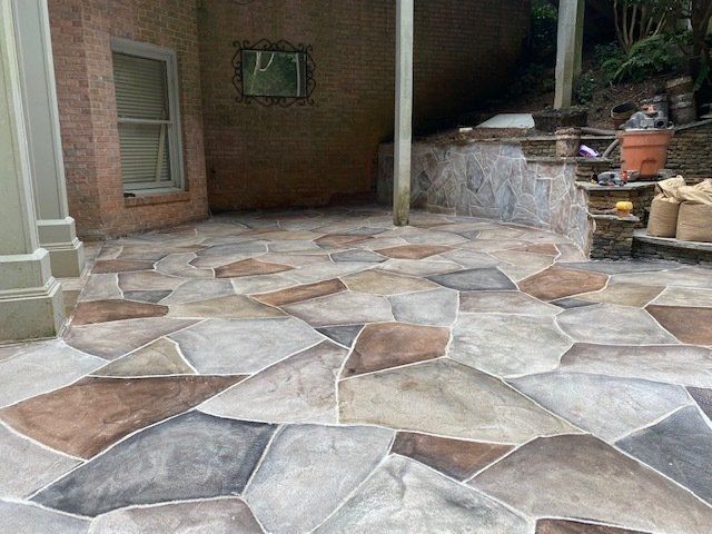 Stone patio with irregular tile pattern beside a brick wall and raised planter area