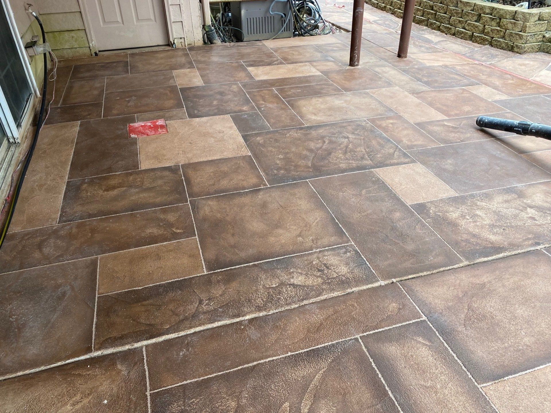 Brown tiled floor in a room with a doorway and cleaning tools in the background