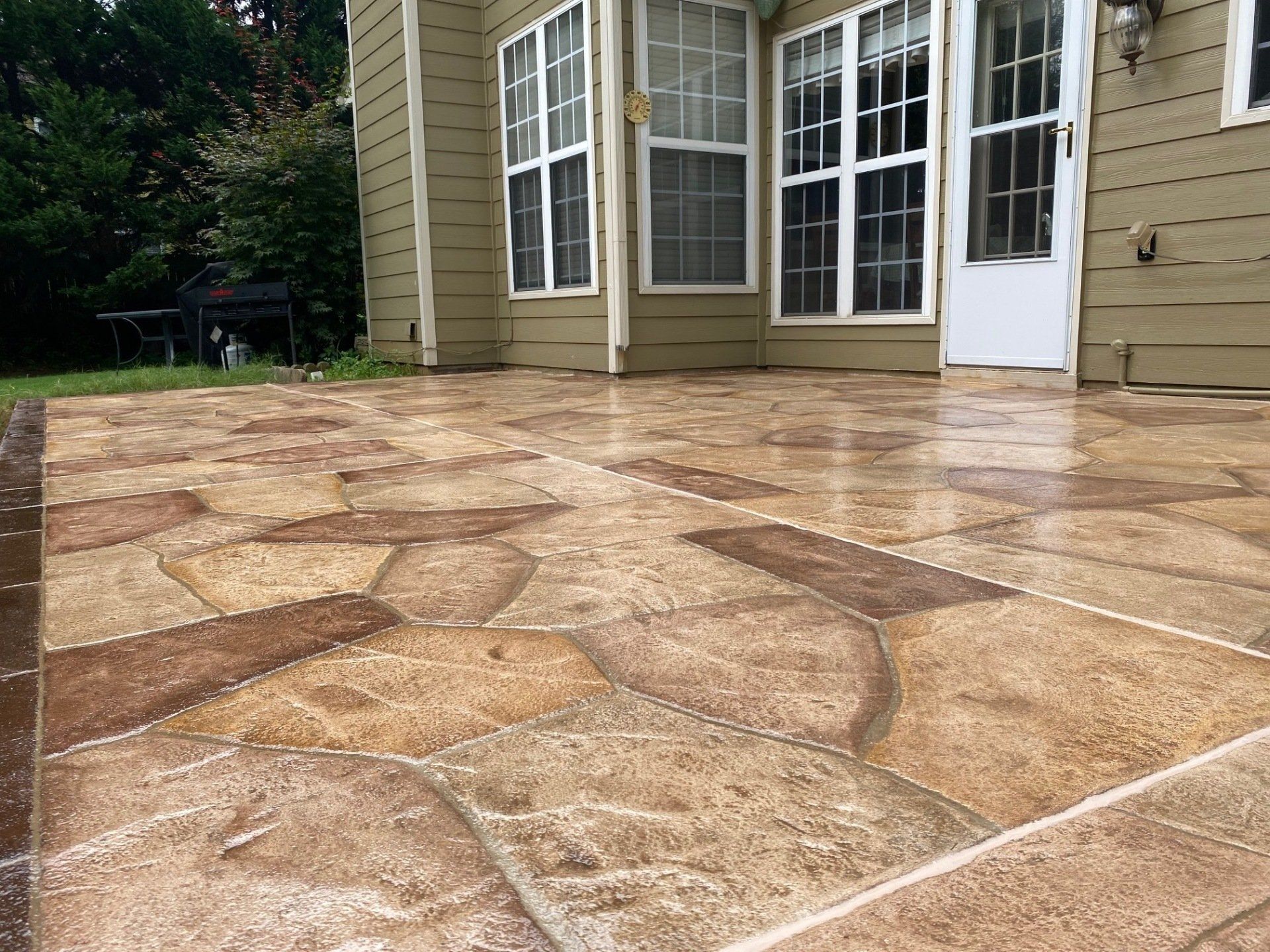 Stamped concrete patio beside a beige house with white French doors and windows