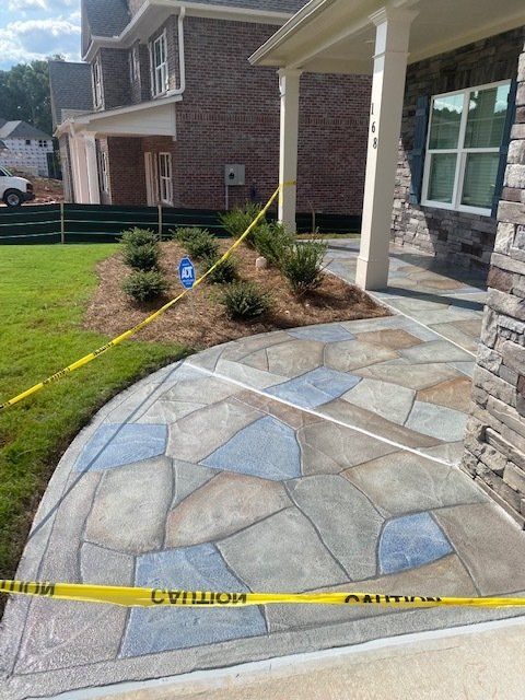 Stone front walkway and porch entrance of a house, with yellow caution tape and a small landscaped bed.