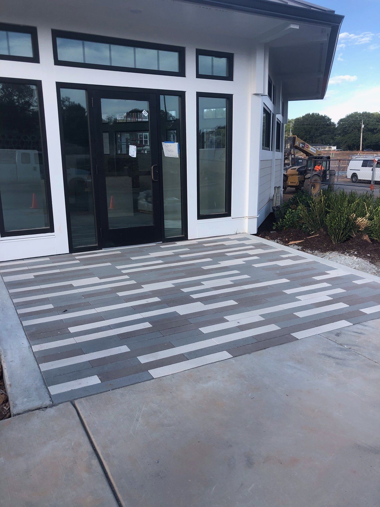 Modern building entrance with glass doors and a striped accessibility ramp leading to the walkway
