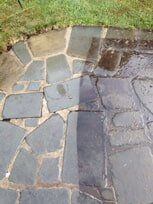 Patio stones partially cleaned by a power washer, revealing a color contrast.
