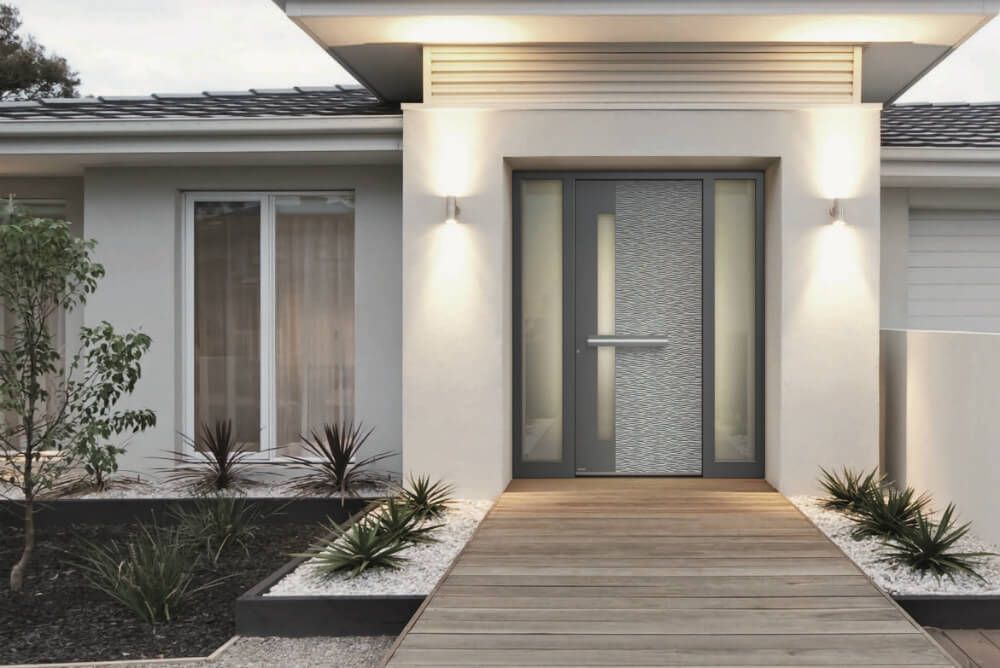 Una casa moderna con un grande portone d'ingresso e una passerella in legno che vi conduce.