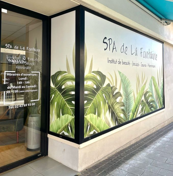 Une devanture de magasin avec une peinture de feuilles tropicales dessus