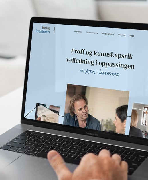 Bilde av en macbook pro på et hvitt bord, med nettsiden til boligkreatøren åpnet i fullskjerm.