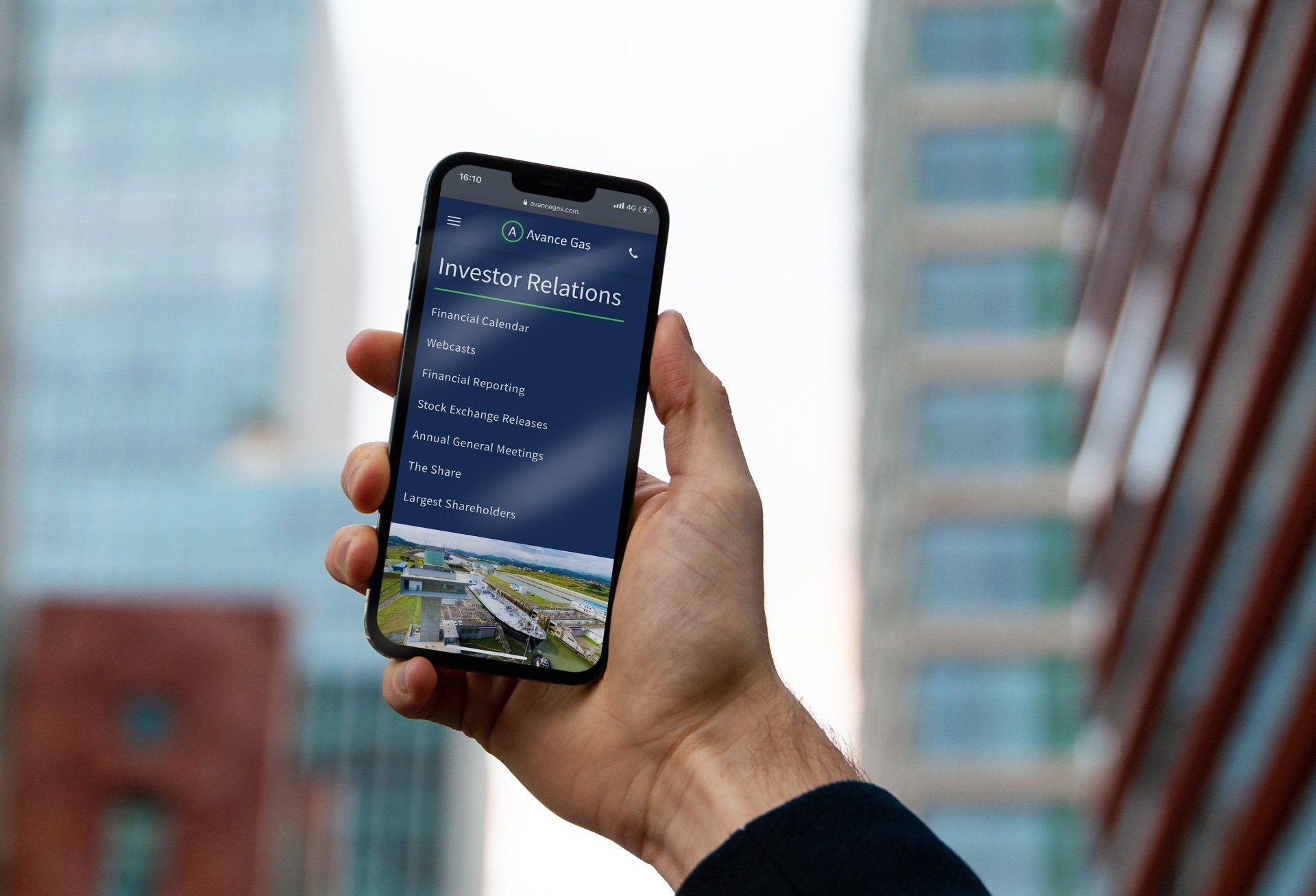 Mockup av nettsiden til Avance Gas, på en iphone X, med bygninger i bakgrunnen (blurry)