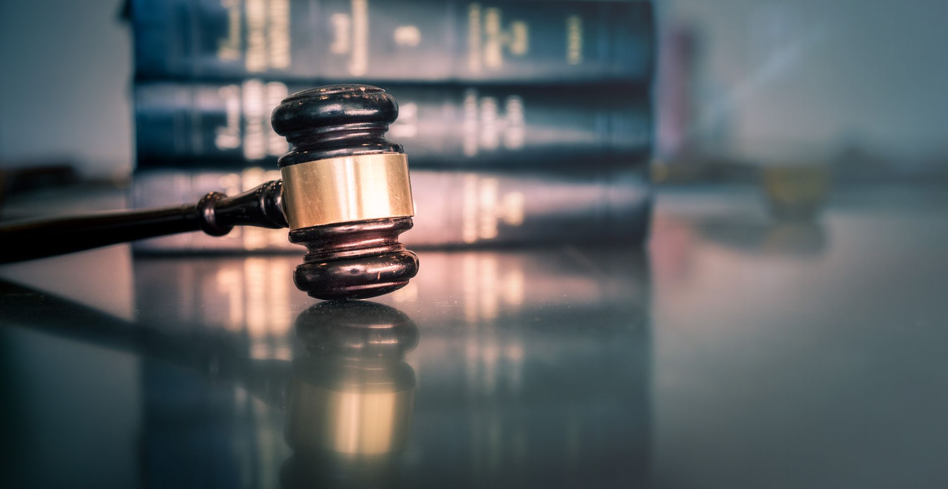 Judge’s gavel on a reflective surface with law books blurred in the background