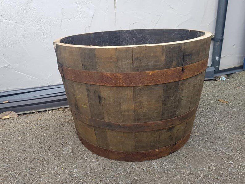 Wooden barrel planter with rusty metal bands, outdoors.