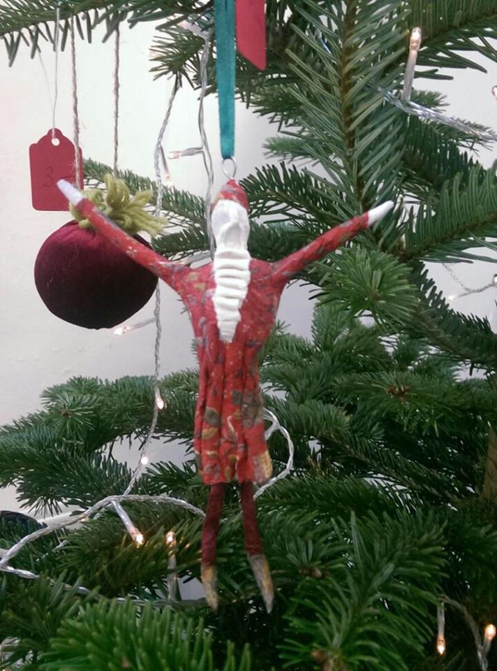 Santa ornament on a Christmas tree; red and white with arms outstretched.
